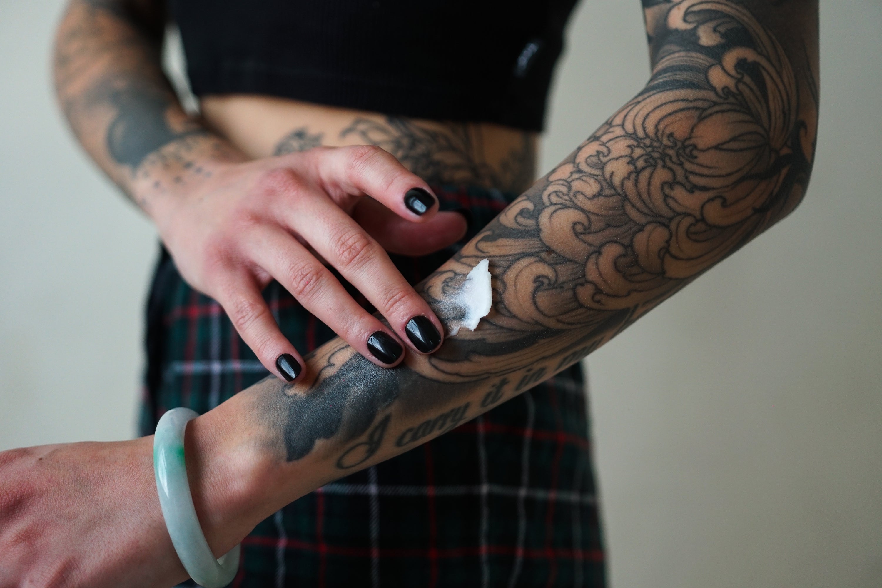 A tattoo artist carefully applying aftercare balm to a freshly inked tattoo, highlighting the importance of moisturizing for tattoo healing.